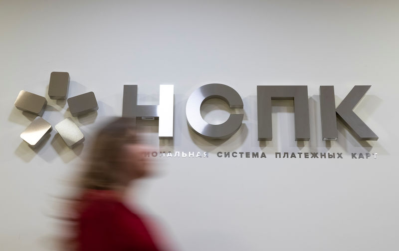 © Reuters. A woman passes in front of a NSPK signage at the company's office in Moscow