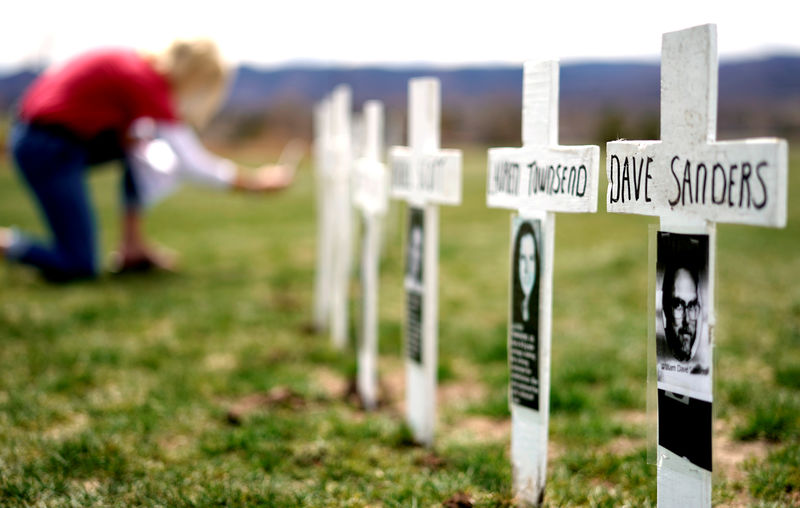 © Reuters. Una mujer mira una línea de cruces que conmemoran a las víctimas de la masacre en la escuela secundaria de Columbine en el aniversario número 20 del ataque en Littleton