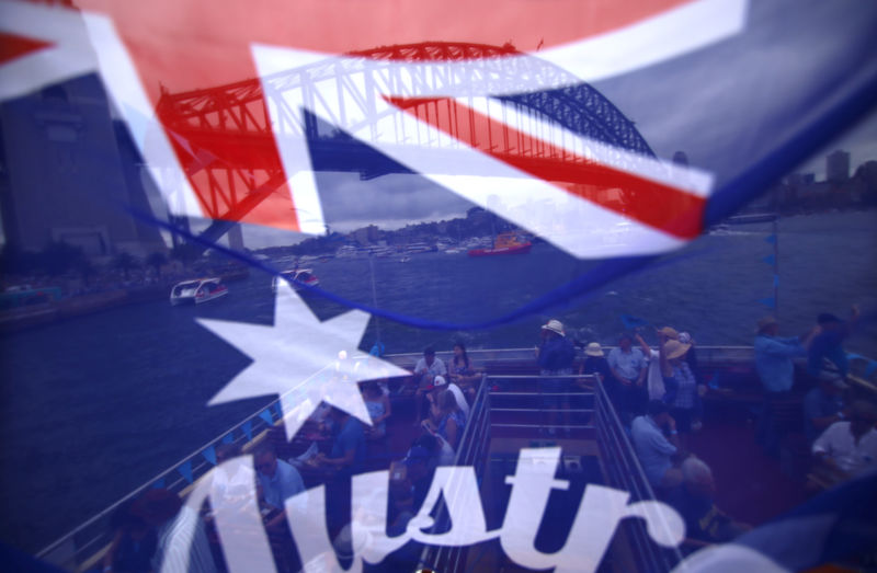 © Reuters. FILE PHOTO:  Passengers aboard a ferry can be seen through an Australian national flag as they participate in celebrations for Australia Day, which marks the arrival of Britain's First Fleet in 1788, on Sydney Harbour
