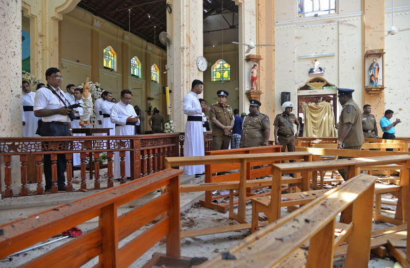 © Reuters. Foto del domingo de oficiales de policía junto a sacerdotes católicos en una iglesia tras un ataque con bombra en Negombo, Sri Lanka