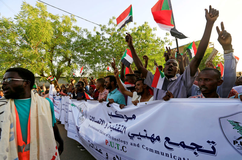 © Reuters. FILE PHOTO: Sudanese demonstrators wave national flags as they attend a mass anti-government protest outside the Defence Ministry in Khartoum