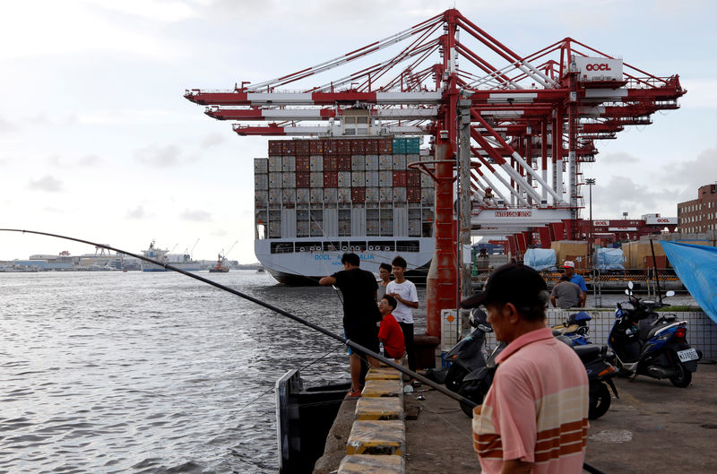 © Reuters. FILE PHOTO:  People fish in front of an Orient Overseas Container Line container ship