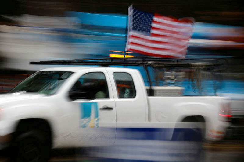 © Reuters. FILE PHOTO: A PG&E truck carrying an American Flag drives past PG&E repair trucks in Paradise