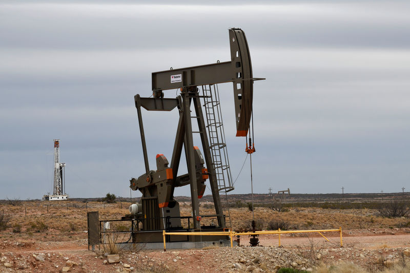 © Reuters. A pump jack operates in front of a drilling rig owned by Exxon near Carlsbad