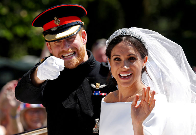 © Reuters. FILE PHOTO: Britain's Prince Harry gestures next to his wife Meghan as they ride a horse-drawn carriage after their wedding ceremony at St George's Chapel