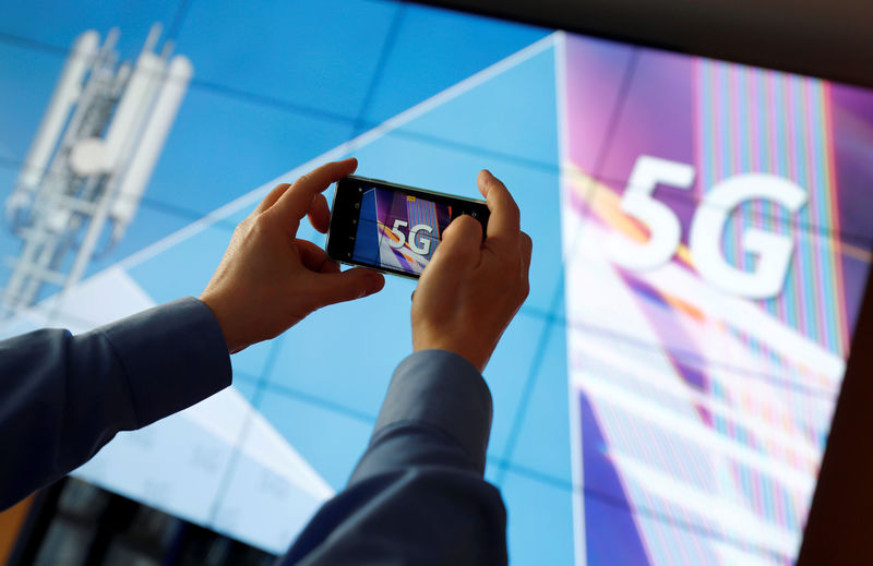 © Reuters. FILE PHOTO: A journalist uses his mobile phone to take a picture of the 5G logo prior to the auction of spectrum for 5G services at the Bundesnetzagentur head quarters in Mainz