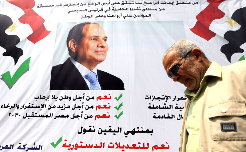 © Reuters. FILE PHOTO: A man walks in front of a banner reading, "Yes to the constitutional amendments, for a better future", with a photo of the Egyptian President Abdel Fattah al-Sisi before the approaching referendum on constitutional amendments in Cair
