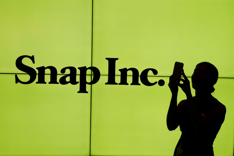 © Reuters. FILE PHOTO: A woman stands in front of the logo of Snap Inc. on the floor of the New York Stock Exchange (NYSE) while waiting for Snap Inc. to post their IPO, in New York City