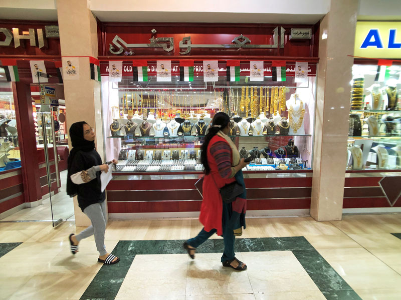 © Reuters. FILE PHOTO - People walk in front of a gold shop in Gold Souq in Abu Dhabi