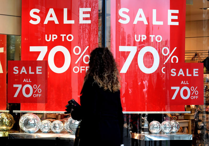 © Reuters. FILE PHOTO: A woman passes sale signs in a shop window in downtown Hamburg