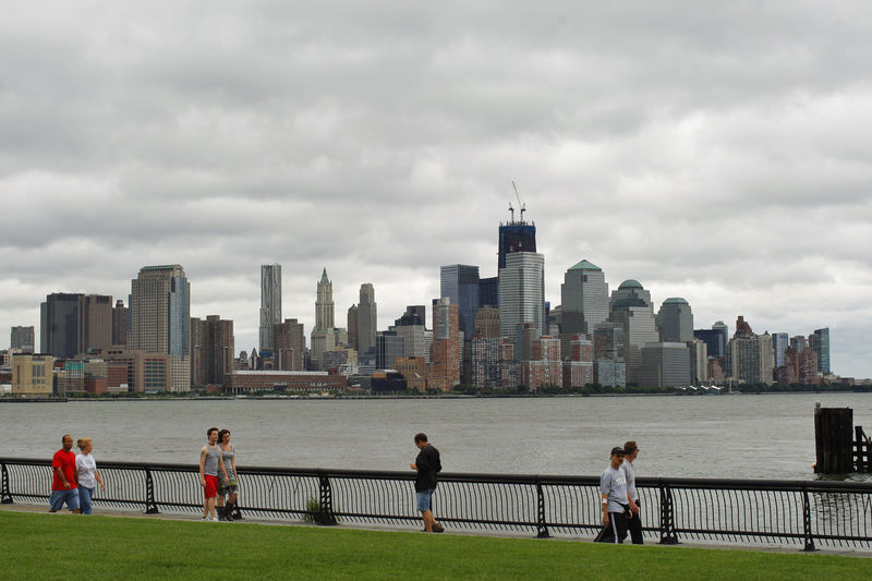 © Reuters. With the skyline of New York behind them, people walk along Hudson river after the pass of Hurricane Irene at Hoboken