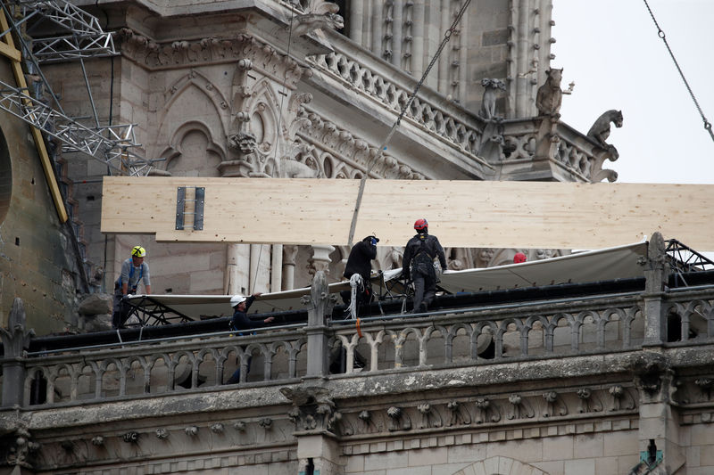 © Reuters. Workers install temporary tarpaulins to protect Notre-Dame Cathedral from rain damage, a week after a massive fire devastated large parts of the gothic structure in Paris