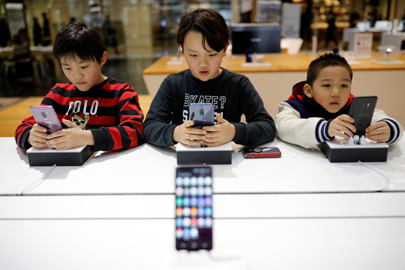 © Reuters. Crianças mexem em telefone celular em loja de Seul