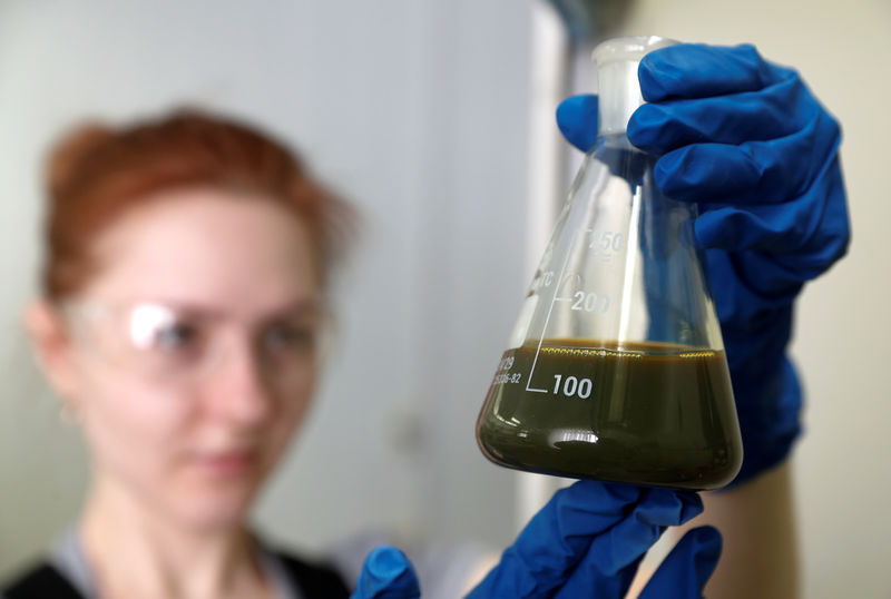 © Reuters. An employee holds a bulb with crude oil at a laboratory in the Irkutsk Oil Company-owned Yarakta Oil Field in Irkutsk Region
