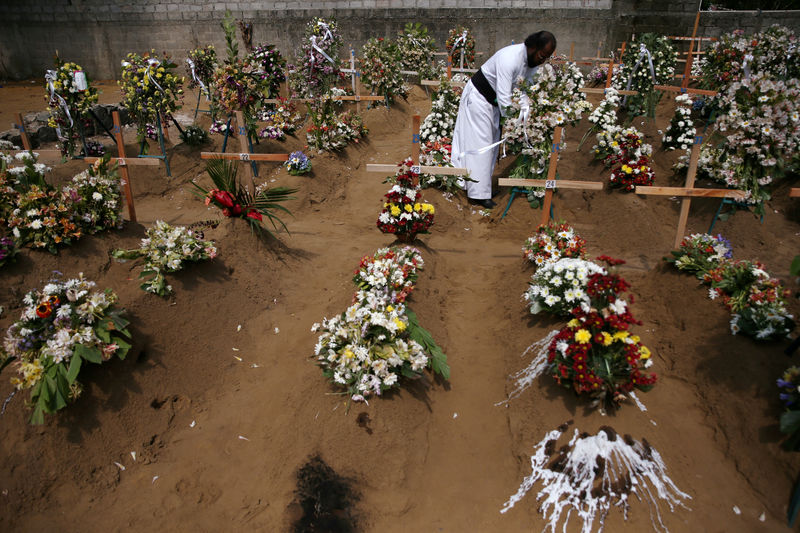 © Reuters. Sacerdote coloca flores em local de funeral coletivo no Sri Lanka