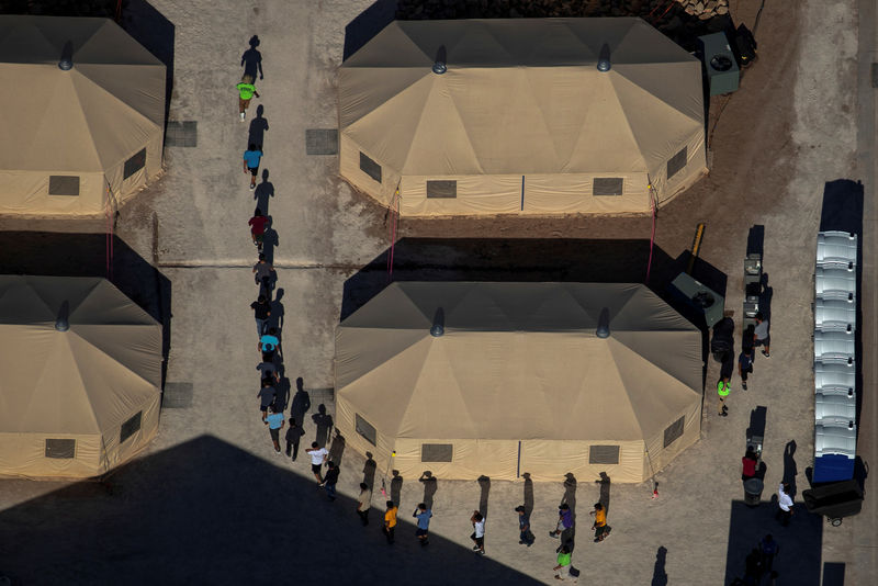 © Reuters. FILE PHOTO: Migrant children are led by staff in single file between tents at a detention facility next to the Mexican border in Tornillo