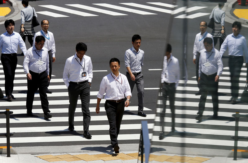 © Reuters. Office workers are reflected in a glass railing as they cross street during lunch hour in Tokyo