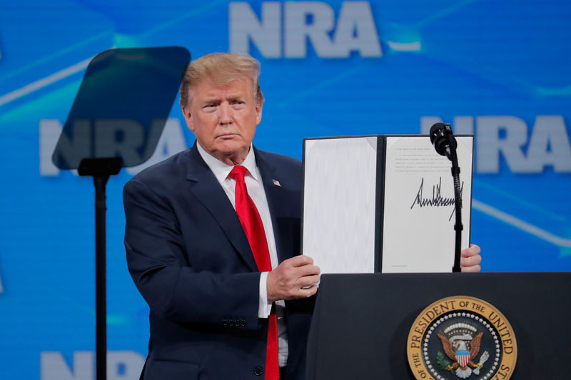 © Reuters. President Trump holds up an executive order with his signature at the annual NRA meeting in Indianapolis