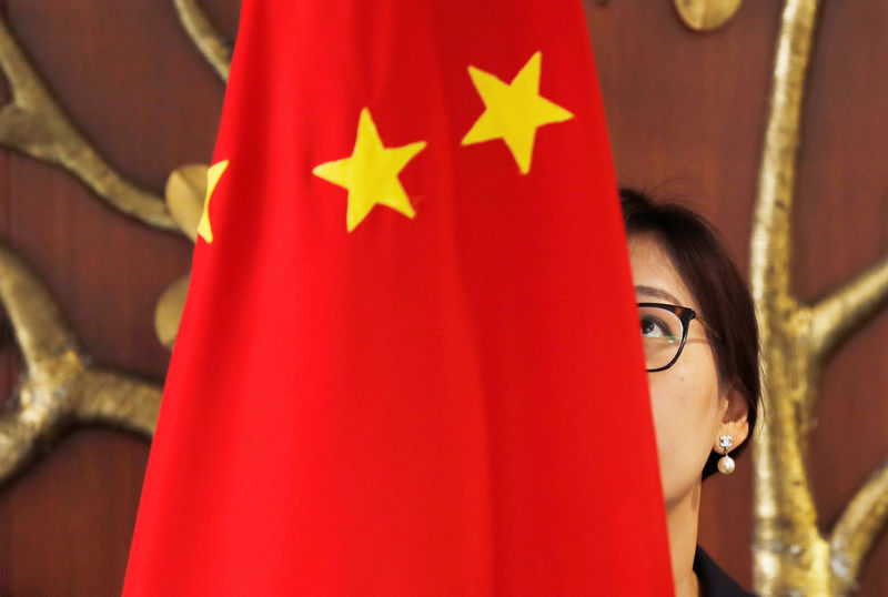 © Reuters. FILE PHOTO - A Chinese official adjusts a Chinese flag before the start of a meeting between Foreign Minister Wang Yi and Indian Foreign Minister Sushma Swaraj in New Delhi