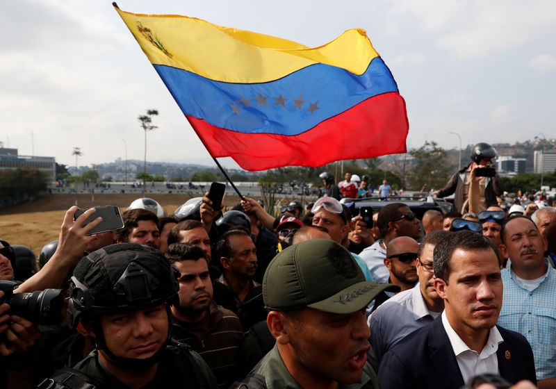 © Reuters. Líder da oposição venezuelana Juan Guaidó fala com jornalistas ao lado de soldados perto de base aérea de La Carlota