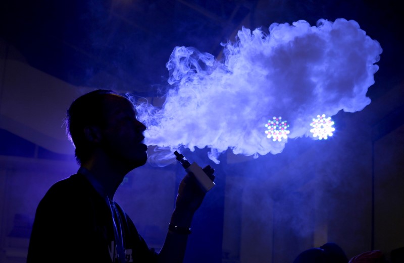 © Reuters. An exhibitor staff member uses an electronic cigarette at VAPE CHINA EXPO in Beijing