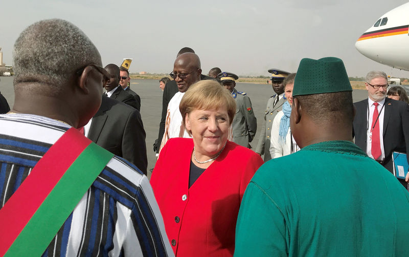 © Reuters. German Chancellor Angela Merkel is greeted by officials as she arrives at the airport near Ouagadougo