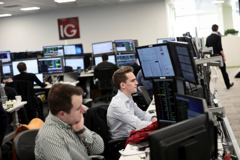 © Reuters. FILE PHOTO:  Traders look at financial information on computer screens on the IG Index trading floor