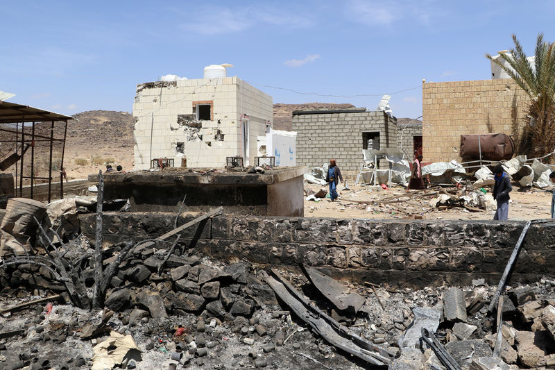 © Reuters. People walk at the scene of an air strike that hit a gas station near a hospital in Kutaf district of the northwestern province of Saada