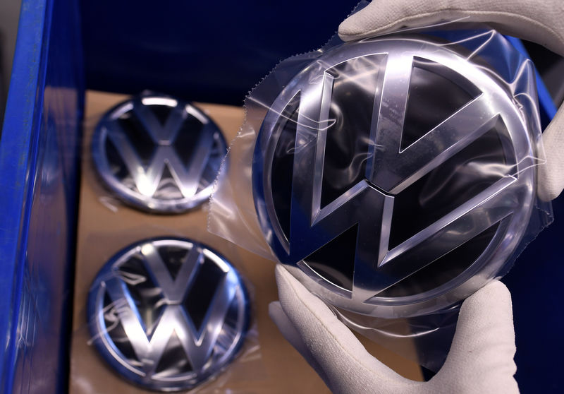 © Reuters. An employee holds a Volkswagen logo in a production line at the Volkswagen plant in Wolfsburg