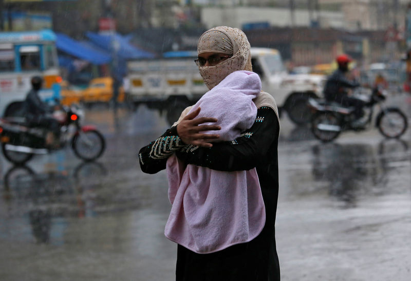 © Reuters. A woman covers her baby as she walks during heavy rains in Kolkata