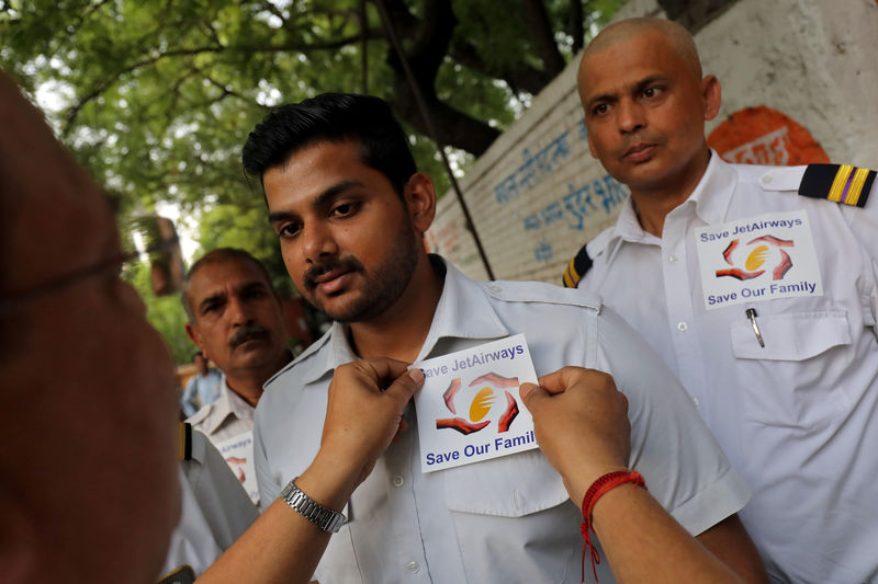 © Reuters. FILE PHOTO: A Jet Airways employee places a sticker on the shirt of his colleague during a vigil demanding to "save Jet Airways" in New Delhi