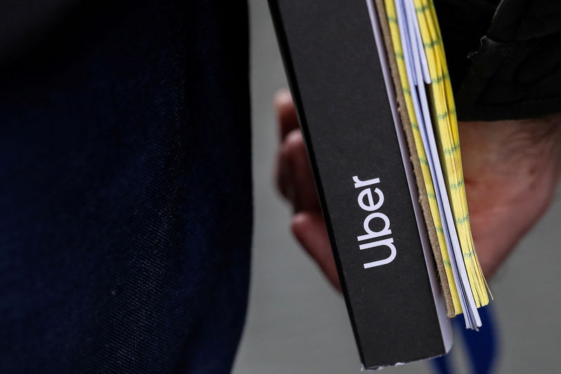 © Reuters. FILE PHOTO: Investor walks out of the Uber roadshow with documents in hand at a hotel in New York