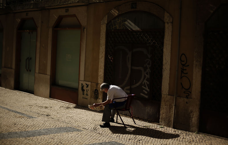 © Reuters. A man reads a newspaper in downtown Lisbon