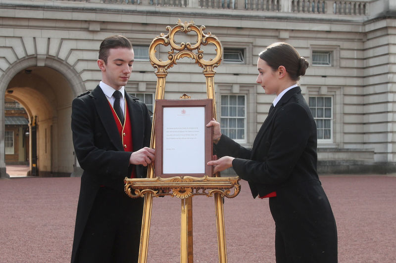 © Reuters. Los pajes Kelly y Thompson colocan un anuncio oficial del nacimiento del hijo del príncipe Enrique y Meghan Markle en un atril en el Palacio de Buckingham, en Londres.