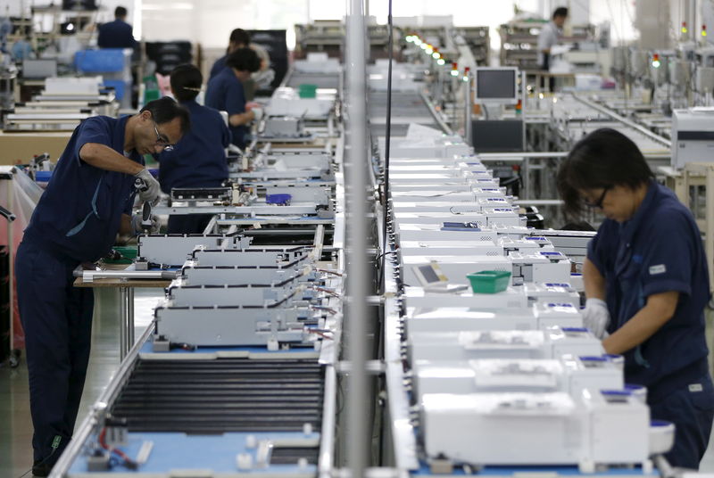 © Reuters. FILE PHOTO: Employees work an assembly line at a factory of Glory Ltd., a manufacturer of automatic change dispensers, in Kazo, north of Tokyo