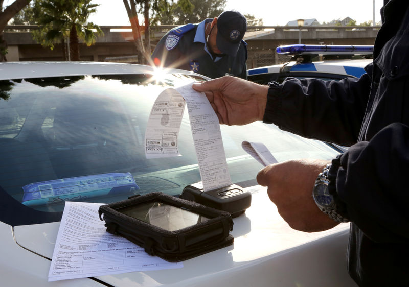 © Reuters. A traffic officer prints out a fine for an Uber driver who operates without a permit in Cape Town