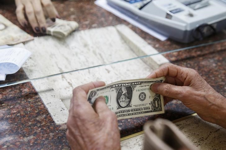 © Reuters. FILE PHOTO: A woman change dollars for bolivars at a money exchange in Caracas