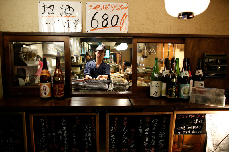 © Reuters. FILE PHOTO: A man cooks a skewered chicken meal, know as Yakitori in Japan, at a Japanese casual style bar and restaurant in Tokyo