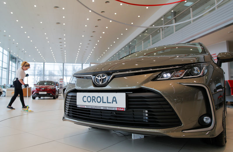 © Reuters. An employee cleans the floor past Toyota Corolla car on display at Rolf, an automotive dealer in Moscow