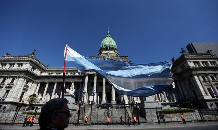 © Reuters. Una persona ondea una bandera argentina frente al Congreso Nacional en Buenos Aires