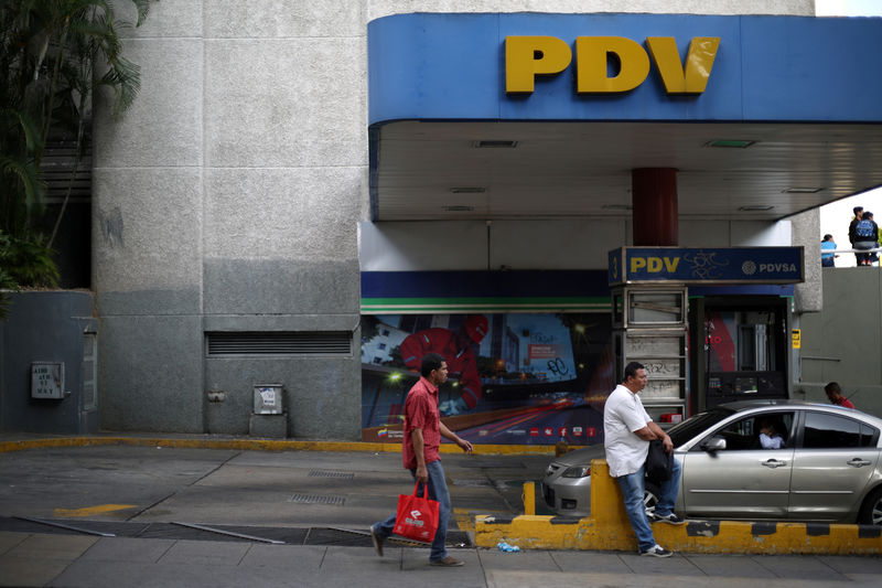 © Reuters. FILE PHOTO: A pedestrian walks next to a PDVSA gas station in Caracas