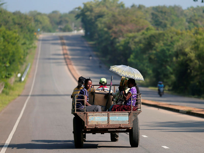 © Reuters. Villagers travel in a tractor on a newly built road in Hambantota