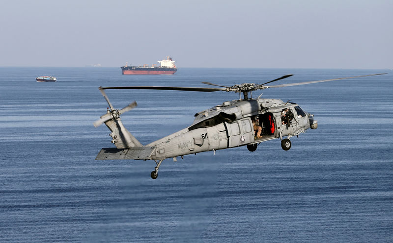 © Reuters. FILE PHOTO: MH-60S helicopter hovers in the air with an oil tanker in the background as the USS John C. Stennis makes its way to the Gulf through the Strait of Hormuz