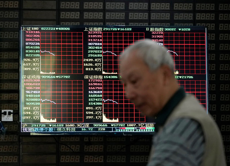 © Reuters. FILE PHOTO: An investor walks past a screen displaying stock information at a brokerage house in Shanghai