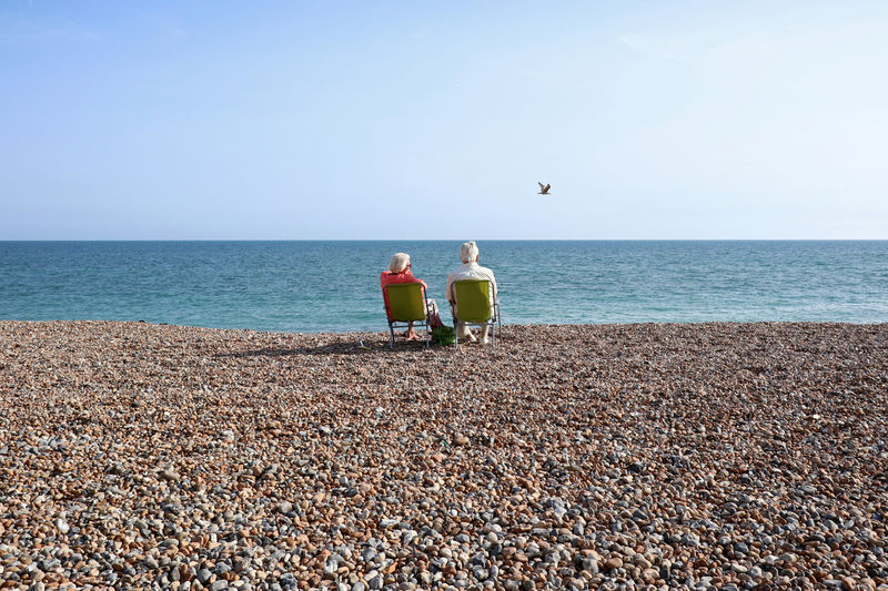 © Reuters. FILE PHOTO: FILE PHOTO: A couple sit on the beach and look out to sea on the August bank holiday weekend in Worthing