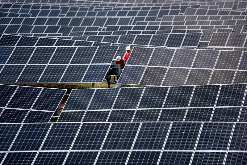 © Reuters. FILE PHOTO: Workers inspect solar panels at a photovoltaic power station on a hill in Linyi