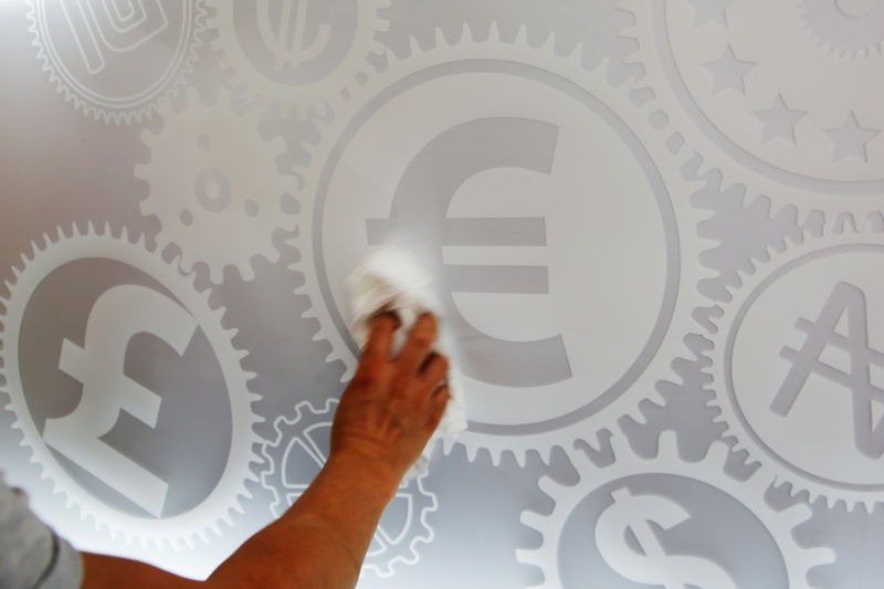 © Reuters. A man cleans a board with different currency signs at a currency exchange office in Madrid