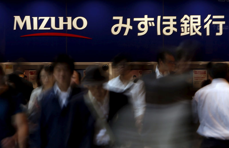 © Reuters. FILE PHOTO: Pedestrians walk under a logo of the Mizuho Financial Group Inc. in Tokyo