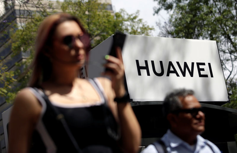 © Reuters. People walk past a Huawei company logo at a bus stop in Mexico City