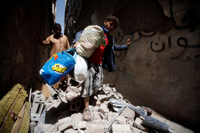 © Reuters. People carry their belongings at the site of an air strike launched by the Saudi-led coalition in Sanaa